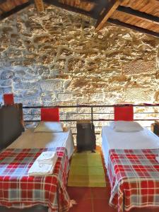 two beds in a room with a stone wall at Cozy house in Águeda 45 m² with shared pool in Urgueira