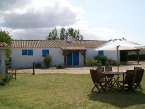 una mesa y sillas con sombrilla frente a una casa en Gîte de La Jolette, en Saint-Jean-de-Monts