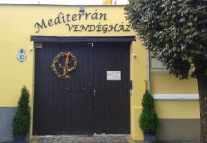 eine schwarze Garagentür mit einem Schild, das mediterrane vegetarische Gerichte liest in der Unterkunft Mediterrán Vendégház in Kecskemét