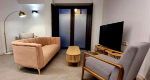 a living room with a couch and a tv at Apartamentos El Dedal de Alcalá in Alcalá de Henares