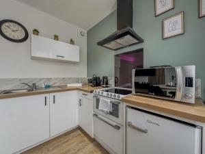 a kitchen with white cabinets and a clock on the wall at MonHac - Modern and comfortable flat in Luisant