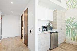 a kitchen with white cabinets and a door to a hallway at Hollywood Studios Condo Costa in Hollywood