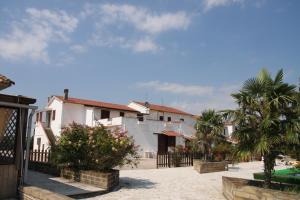 a group of buildings with palm trees and a fence at Hotel Dory in Albinia