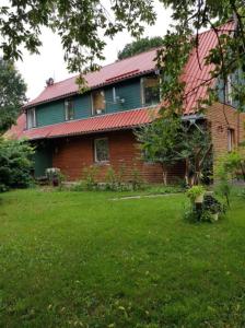 a house with a red roof and a green yard at Šilas in Degučiai