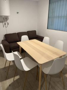 a wooden table with white chairs and a couch at Loft San Carlos in Alicante
