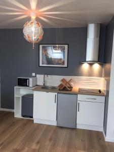 a kitchen with white cabinets and a sink and a chandelier at Appt au pied de la cathédrale avec parking gratuit in Amiens