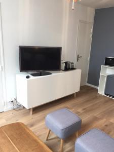 a living room with a white entertainment center with a flat screen tv at Appt au pied de la cathédrale avec parking gratuit in Amiens