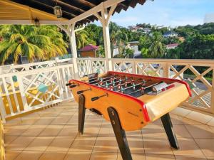 a foosball table on the balcony of a house at Appartement spacieux aux Trois-Îlets avec piscine partagée in Les Trois-Îlets