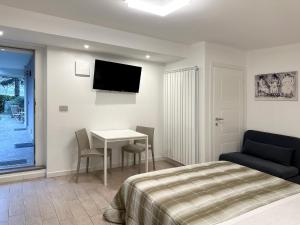 Un dormitorio con una cama, una mesa y un televisor. en BB Nuova Villa Paradiso, en Urbino