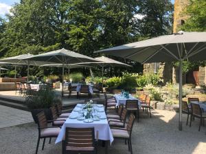 eine Gruppe von Tischen und Stühlen mit Sonnenschirmen in der Unterkunft Hotel Elfbuchen in Kassel