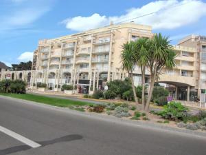 a building with a palm tree in front of a street at Charmant studio vue mer à Pornichet 30 m² avec terrasse in Pornichet