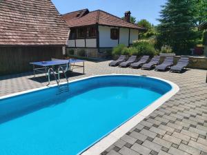 a swimming pool with a table and chairs next to a house at Pool Village House Breznica in Brežnica