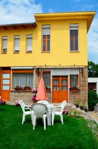 a table and chairs in front of a yellow house at Mediterrán Vendégház in Kecskemét