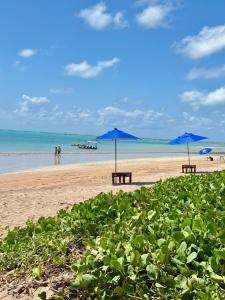 two picnic tables and blue umbrellas on a beach at Seaesta Milagres in São Miguel dos Milagres
