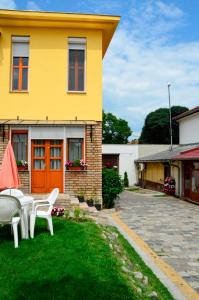 żółty dom z białymi krzesłami na dziedzińcu w obiekcie Mediterrán Vendégház w mieście Kecskemét