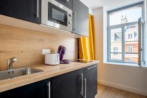- une cuisine avec un évier et un comptoir avec une fenêtre dans l'établissement Au Nouveau Boulonnais - 4 appartements charmants pour couples, familles et groupe d'amis, vieille ville et centre ville de Boulogne sur Mer, à Boulogne-sur-Mer