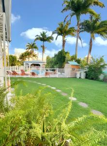 a yard with palm trees and a white fence at Villa de luxe à Saint Francois, piscine in Saint-François