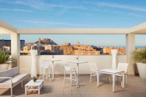 a balcony with tables and chairs and a view of the city at NH Alicante in Alicante