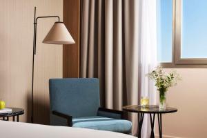 a room with a chair and a table with a vase of flowers at NH Alicante in Alicante