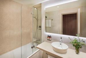 a bathroom with a sink and a glass shower at NH Alicante in Alicante