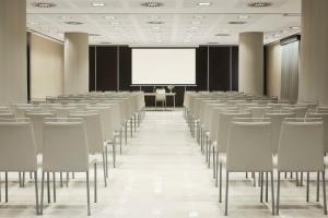 an empty conference room with chairs and a white screen at NH Alicante in Alicante