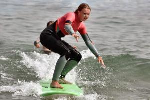 a woman riding a wave on a surfboard in the ocean at Cozy house in Peniche, 30 m² with sea view in Peniche