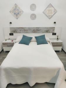 a bedroom with a large white bed with blue pillows at Charming chalet in Prado del Rey with private pool in Prado del Rey
