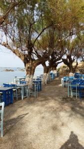 a row of blue tables and chairs under a tree at Melani Apartments in Chania