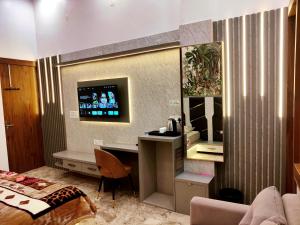 范兰德凡Premium Homestay Near Banke Bihari Ji with Power Backup - Free WiFi - Washing Machine etc的酒店客房设有一张桌子和一台墙上的电视。
