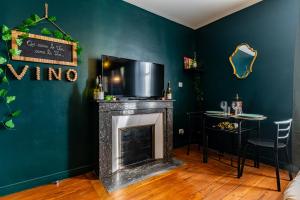 a living room with a fireplace with a tv and a table at Le Clos Épicurien - Voyage a Dijon in Dijon