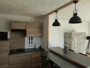 a kitchen with wooden cabinets and a table and two lights at Titi de la Lisathi in Cruéjouls
