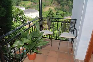 einen Balkon mit zwei Stühlen und einer Pflanze in der Unterkunft Charming apartment with pool in San Antolin 30 m² and garden in San Antolín