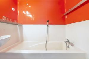 une salle de bain avec une baignoire et un mur orange dans l'établissement Studio confortable à Bourg-Saint-Maurice, 30 m², vue montagne, à Bourg-Saint-Maurice 5 autres photos
