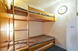 une chambre avec des lits superposés avec une horloge au mur dans l'établissement Studio confortable à Bourg-Saint-Maurice, 30 m², vue montagne, à Bourg-Saint-Maurice