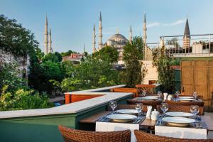 eine Terrasse mit Tischen und Stühlen und Blick auf die Moschee in der Unterkunft Hotel Erguvan - Special Category in Istanbul