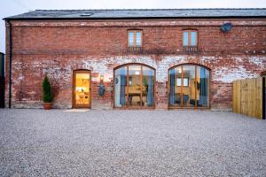 una casa in mattoni con porte in vetro sul vialetto di Sleeps 28 I Luxurious 3-Barn Retreat I 3 Hot Tubs I Games room a Preesgreen