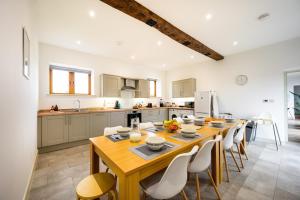 una cucina con un tavolo di legno e sedie bianche di Sleeps 28 I Luxurious 3-Barn Retreat I 3 Hot Tubs I Games room a Preesgreen