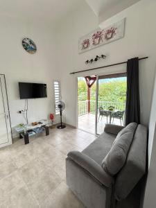 a living room with a couch and a sliding glass door at Lavann Wouj - Proche des plages et du Bourg in Anse-Bertrand
