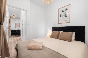 a bedroom with a large white bed with a black headboard at Coco Premium Warszawa Radość in Warsaw