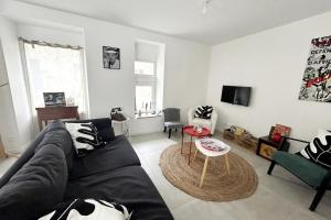 a living room with a black couch and a table at TY BIHAN Plage à 300m Bourg 500m in Piriac-sur-Mer