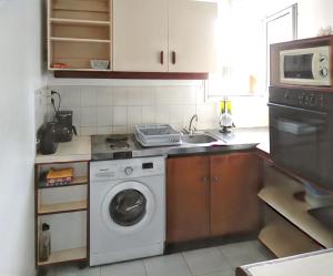 a kitchen with a washing machine and a sink at Appartement confortable à Sainte-Anne, piscine partagée in Sainte-Anne
