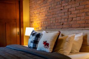a bed with pillows on it with a brick wall at The Historic 901 Condos In the Heart of Fernie in Fernie