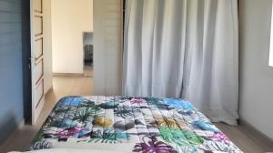 una camera da letto con un letto con una trapunta colorata di Bungalow charmant Le Moule + Jardin a Le Moule Altre 4 foto