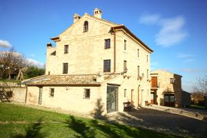 an old stone building with a gate in a field at I Sassi Di San Giuseppe in Montegiorgio