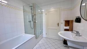 ein weißes Badezimmer mit einer Badewanne und einem Waschbecken in der Unterkunft Sunset I Lakeview I BBQ ღLiboria in Herrsching am Ammersee