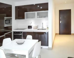 una cucina bianca con tavolo bianco e sedie bianche di Modern Apartment in Lagos + Pool a Lagos