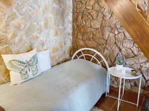 a bedroom with a stone wall with a bed and a table at Charming House in Barão de São Miguel in Barão de São Miguel