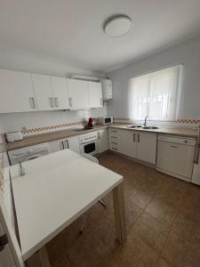 cocina con armarios blancos y mesa blanca en Casa Turquesa, en San José