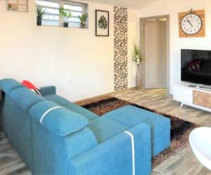 a blue couch in a living room with a clock at Maison accueillante à La Trinité avec piscine partagée 57 m² in La Trinité