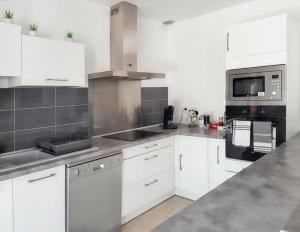 kuchnia z białymi szafkami i piekarnikiem w obiekcie Maison charmante à Monteux avec jardin et équipements complets w mieście Monteux